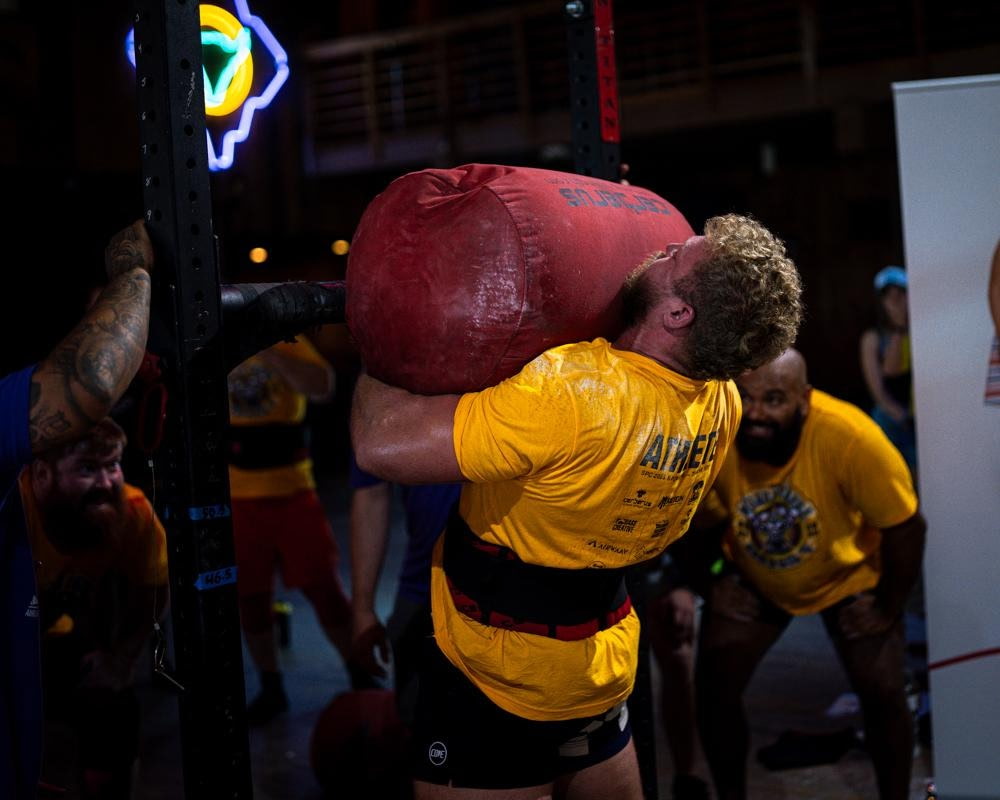 Athlete shouldering a sandbag at a strongman event