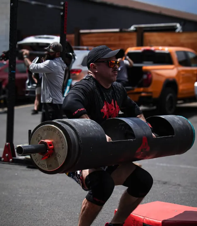 Strongman athlete lifting a log outdoors